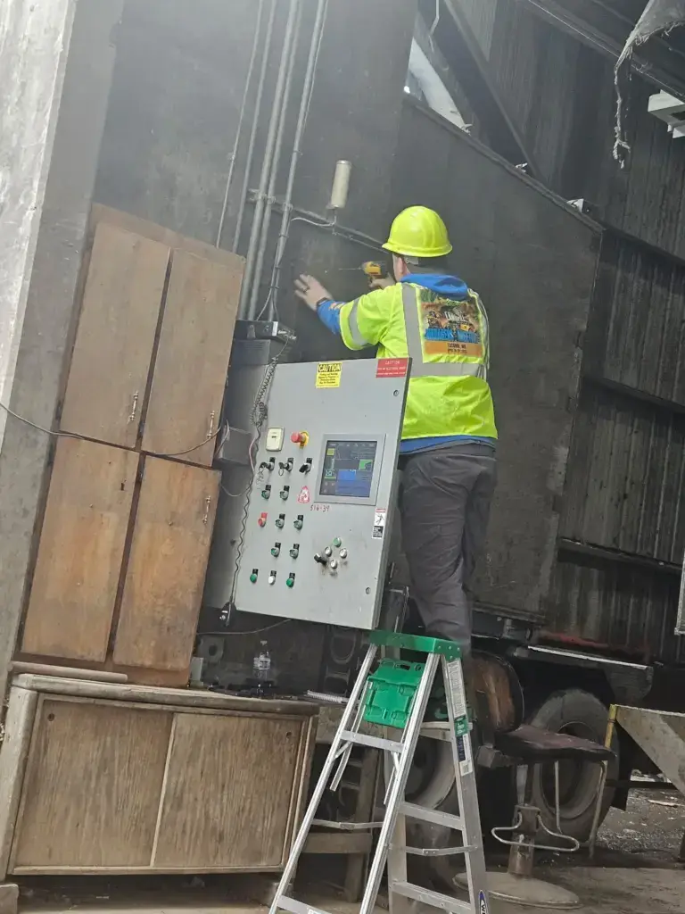 ZehmTV technician performing a commercial TV installation inside an industrial waste management facility in Washington State