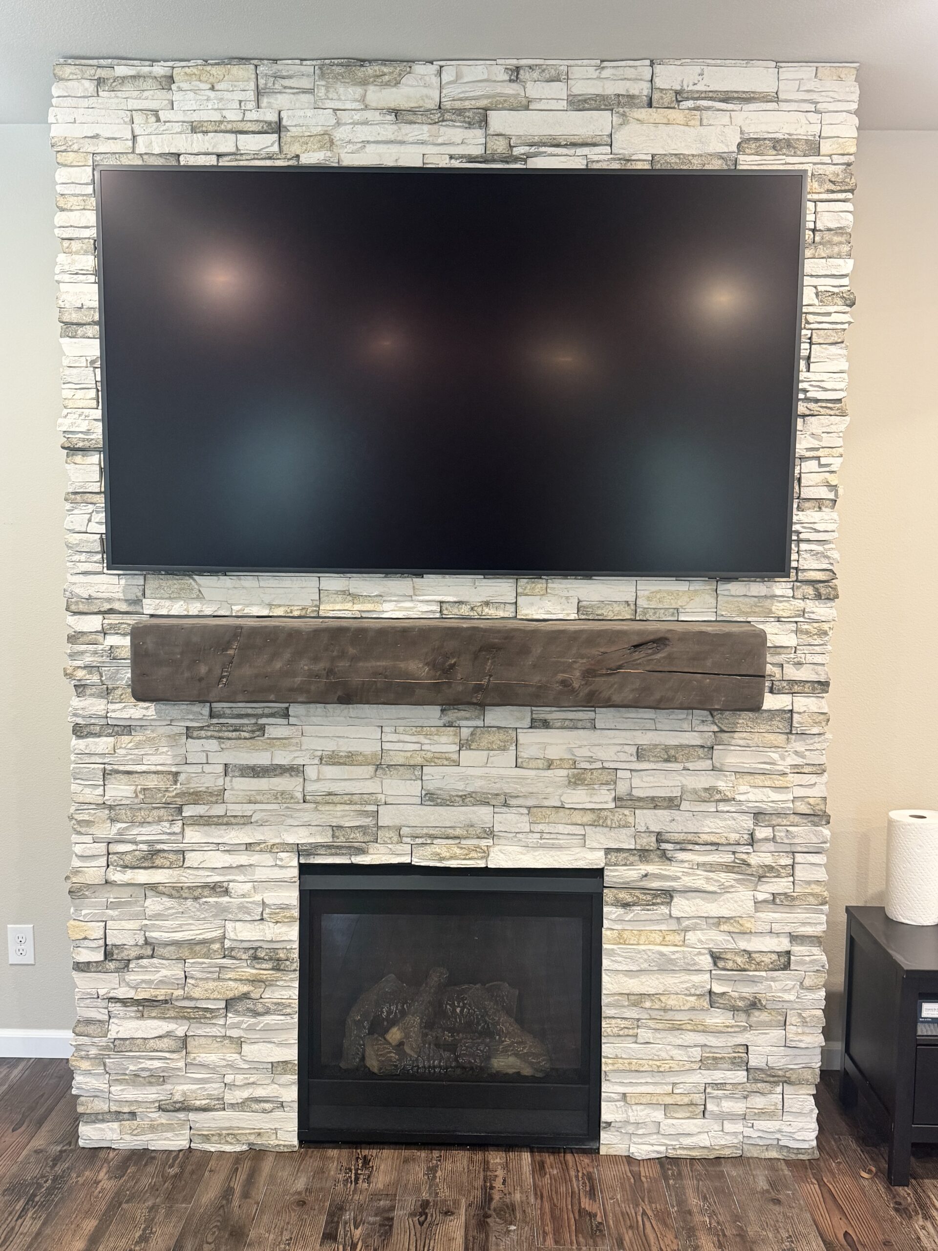 TV mounted above a stone fireplace and wood mantel