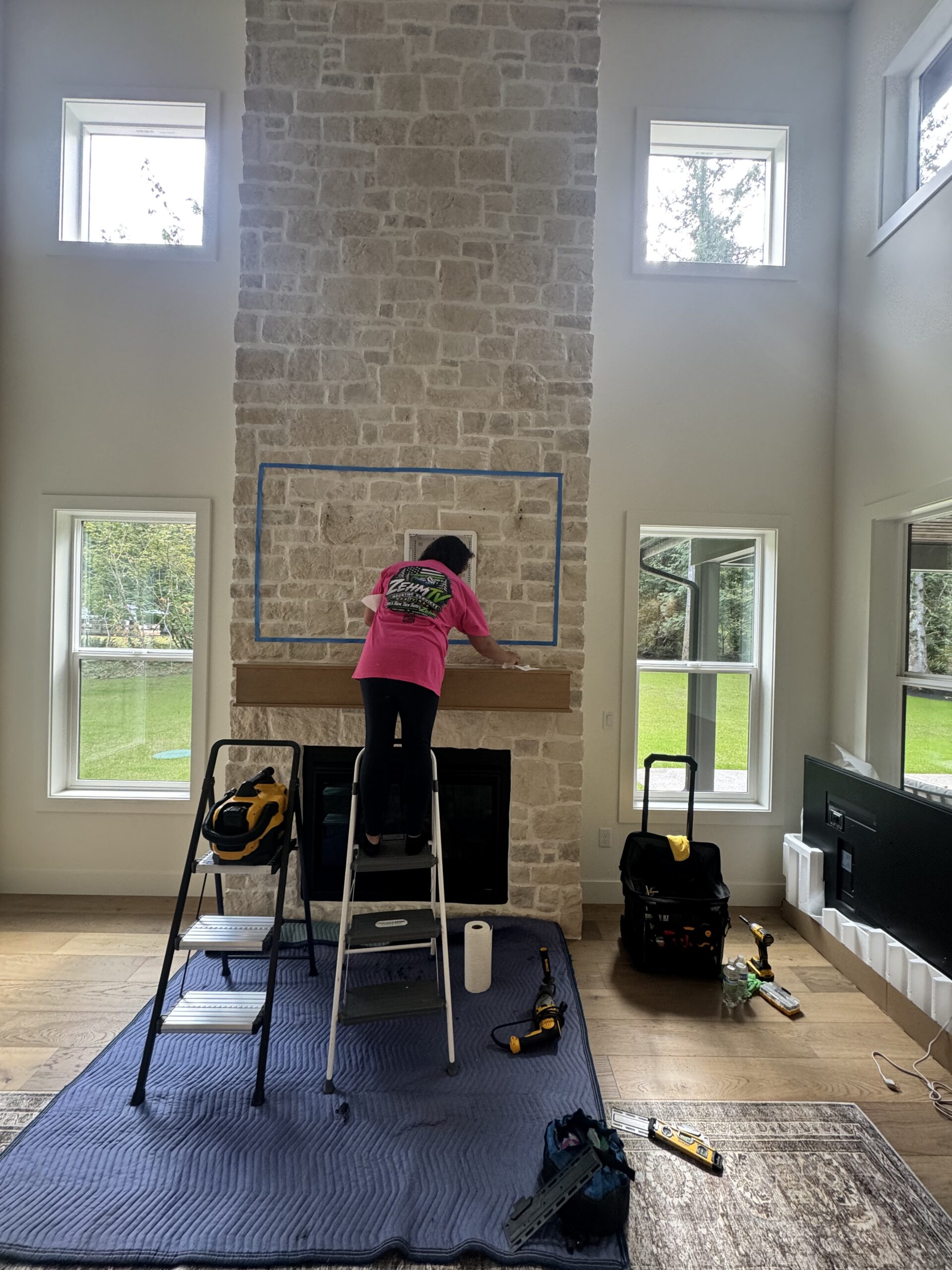ZehmTV installer preparing TV placement above a tall stone fireplace